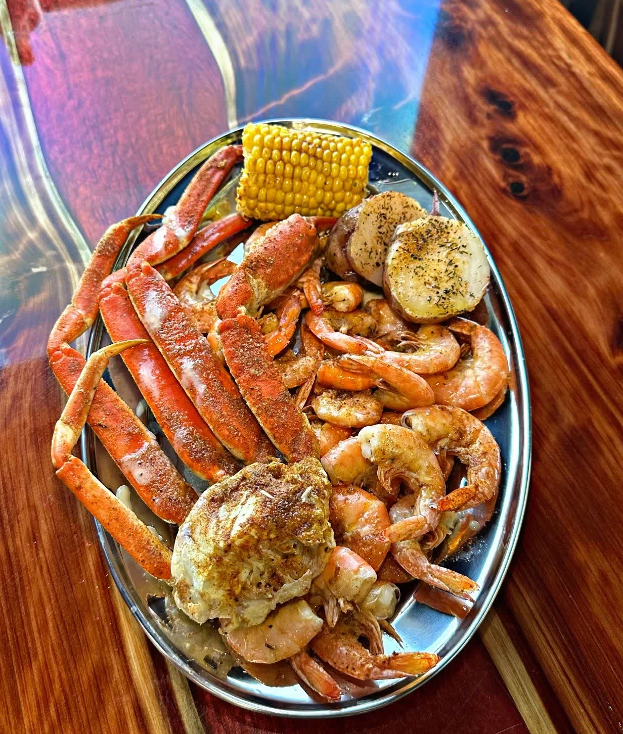 A platter of snow crab legs, corn, potatoes and seasoned shrimp