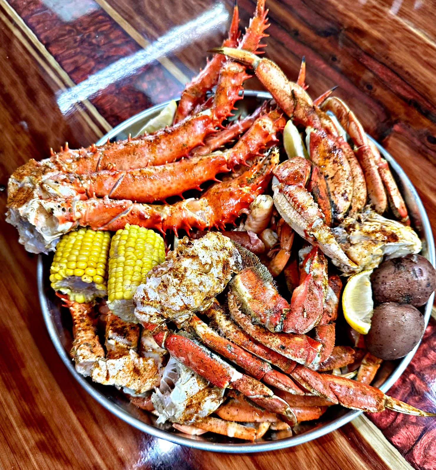 A tray stacked with king crab and snow crab legs, corn and red potatoes